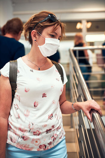 Woman wearing mask standing on staircase at mall