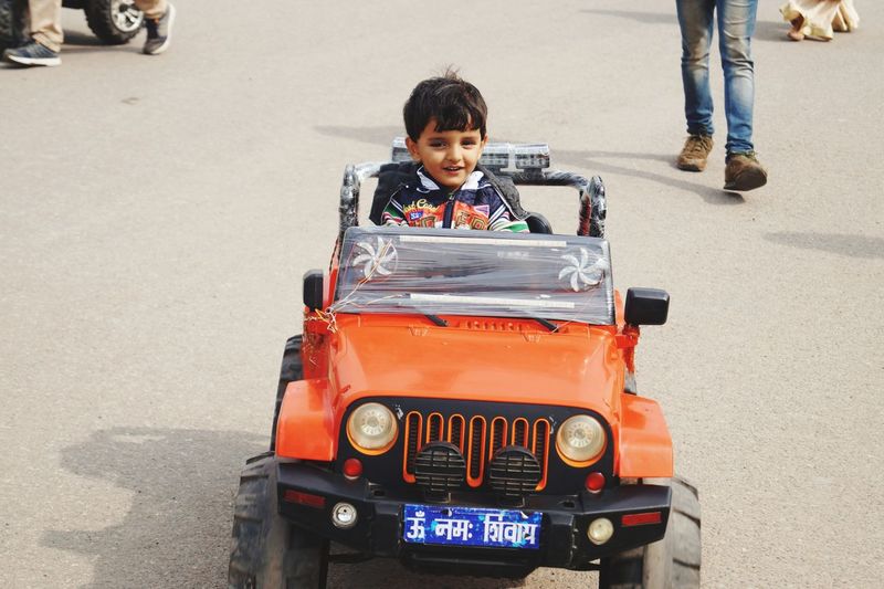 Portrait of boy sitting in toy car
