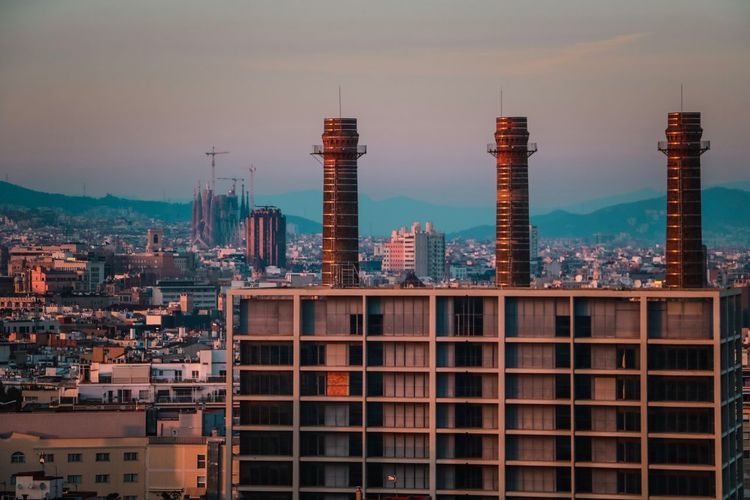 Modern buildings in city against sky during sunset