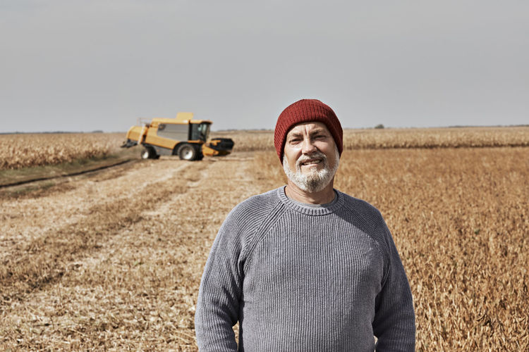 Smiling farmer standing at field during sunny day
