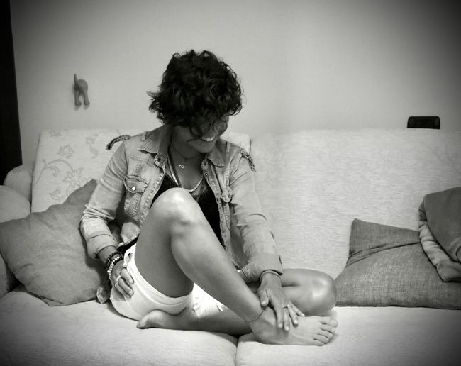 Young woman sitting on sofa at home