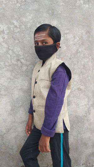 Side view of boy standing against wall