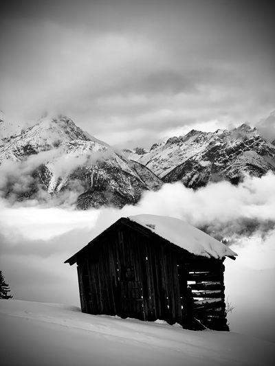 Barn  on snow covered mountain against sky