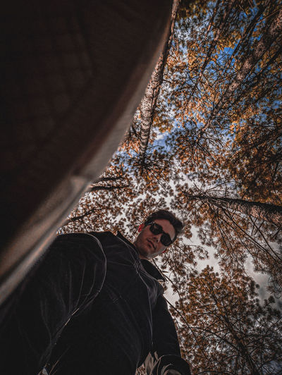 Low angle view of young man standing against trees