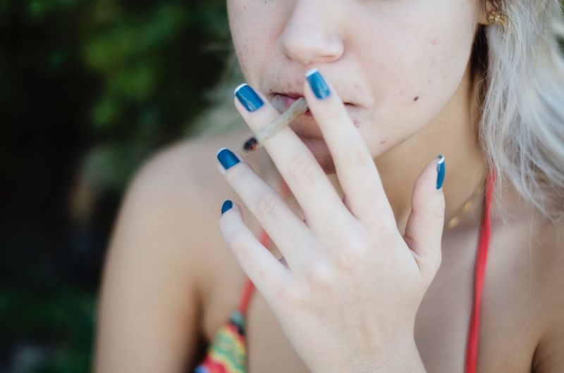 Midsection of woman smoking marijuana joint