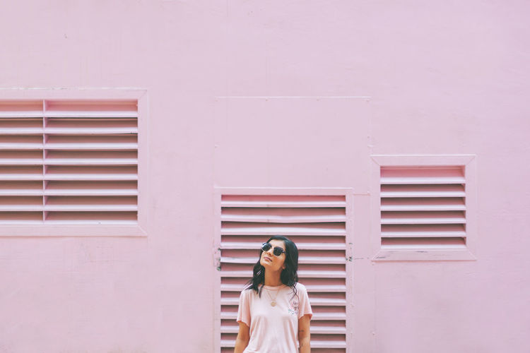Woman standing against pink wall