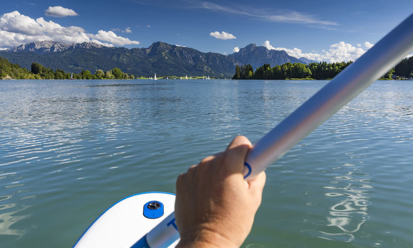 Cropped image of person holding pole in boat on lake