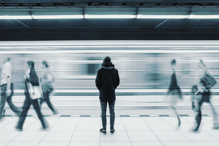 Rear view of man standing amidst crowd at railroad station platform
