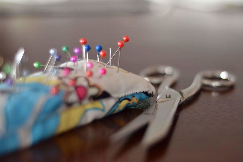 Close-up of colorful sewing pins and scissor on table