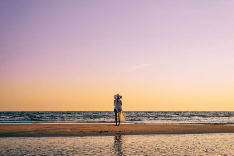 Man standing on beach against sky during sunset