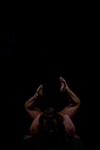 Woman exercising against black background