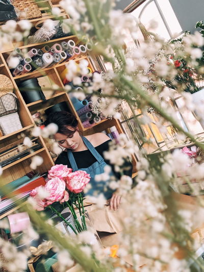Low angle view of woman with pink flower in store