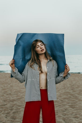 Woman with fully unbuttoned shirt standing at beach