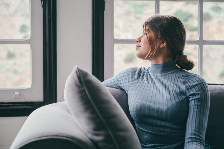 Side view of young woman looking through window