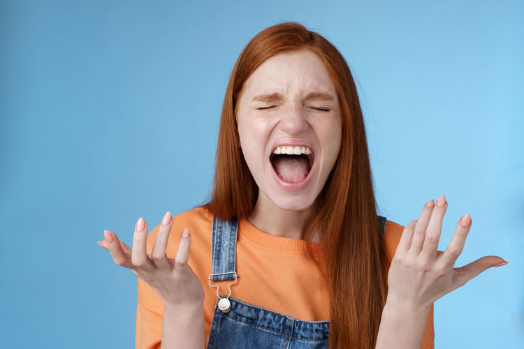Angry woman shouting against blue background