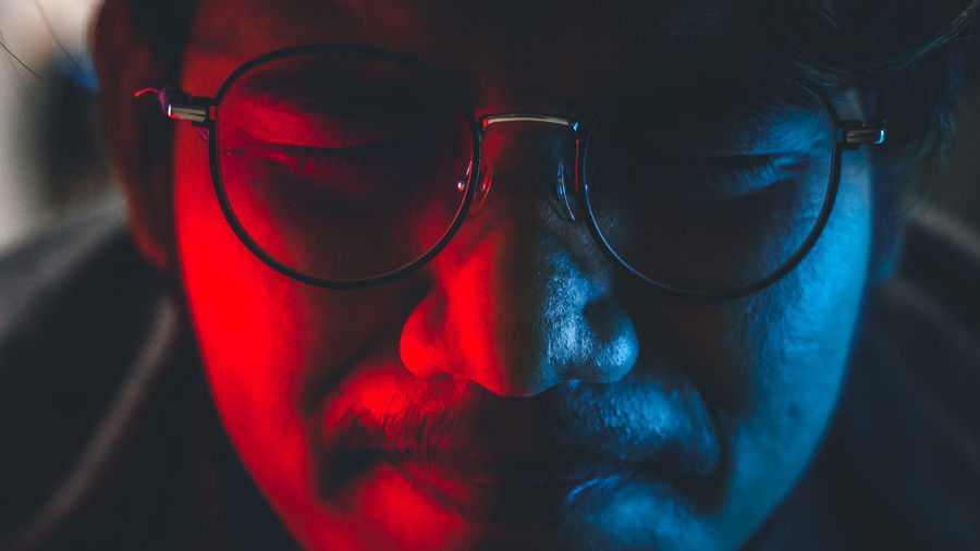 Close-up of man wearing eyeglasses sleeping in darkroom