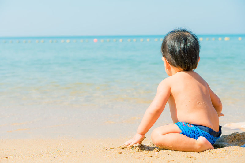 Rear view of boy sitting on beach