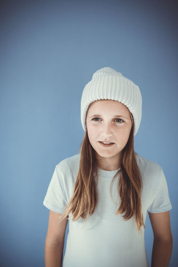 Portrait of smiling young woman against blue background