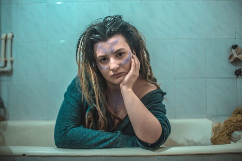 Portrait of young woman sitting in bathroom