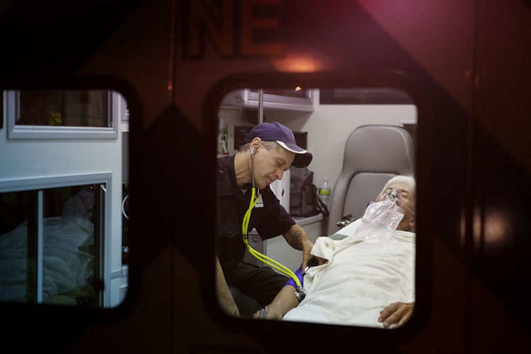 Rescue worker examining patient with stethoscope in ambulance