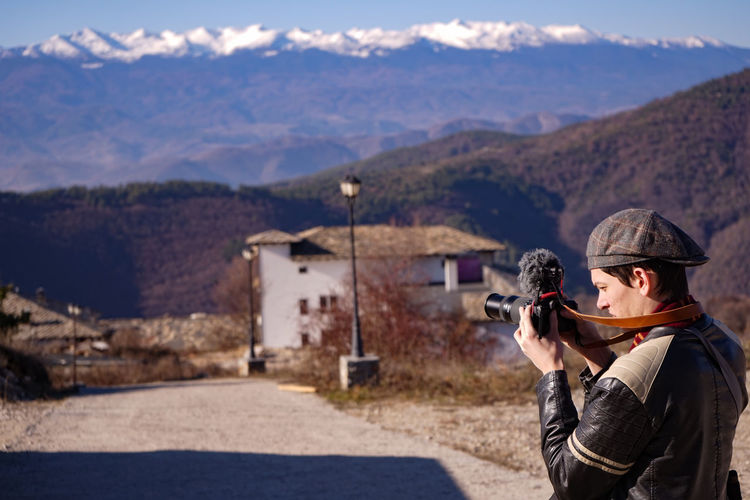 Man holding camera while standing on mountain road