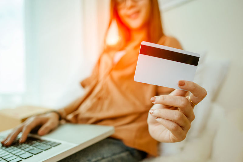 Midsection of woman holding credit card at home