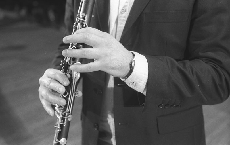 Midsection of man playing clarinet while standing at studio