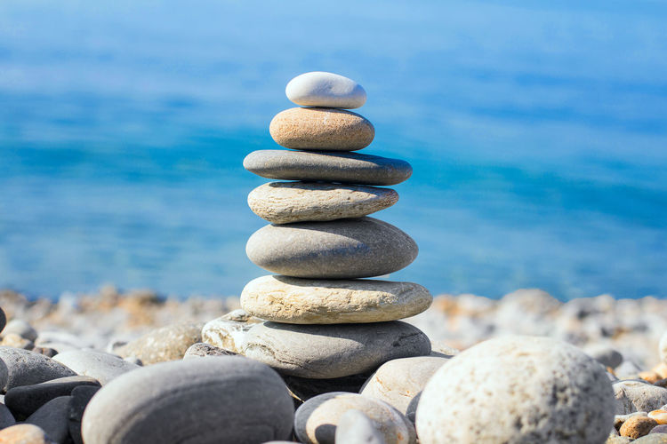 A pyramid of pebbles on the beach against the background of sea water. balance. front view. macro