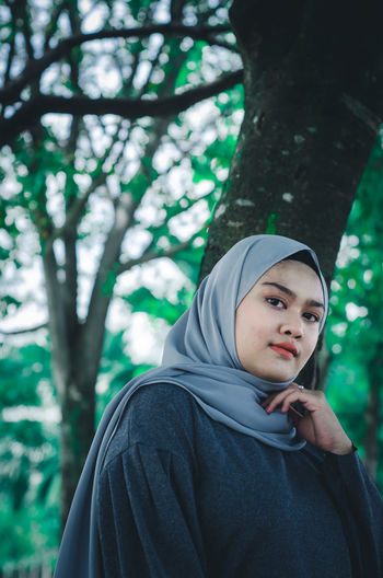 Portrait of young woman wearing hijab against tree