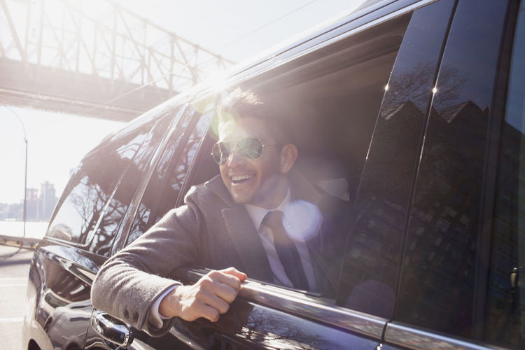 Young businessman looking out the window sitting in car service limousine
