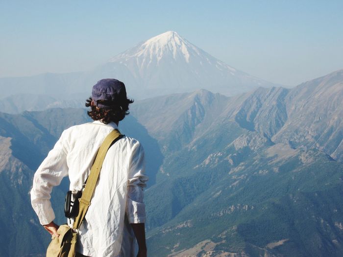 Rear view of man looking at mount damavand against sky