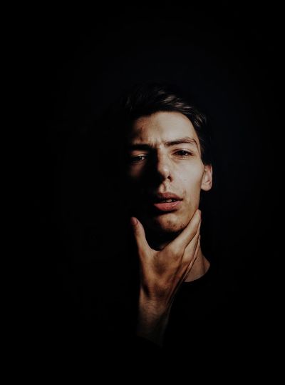 Portrait of young man against black background