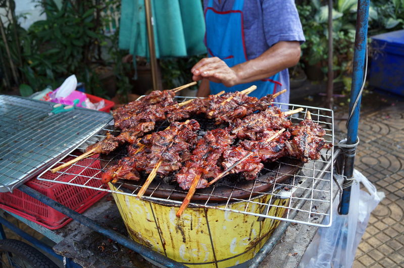 Midsection of man grilling meat on barbecue