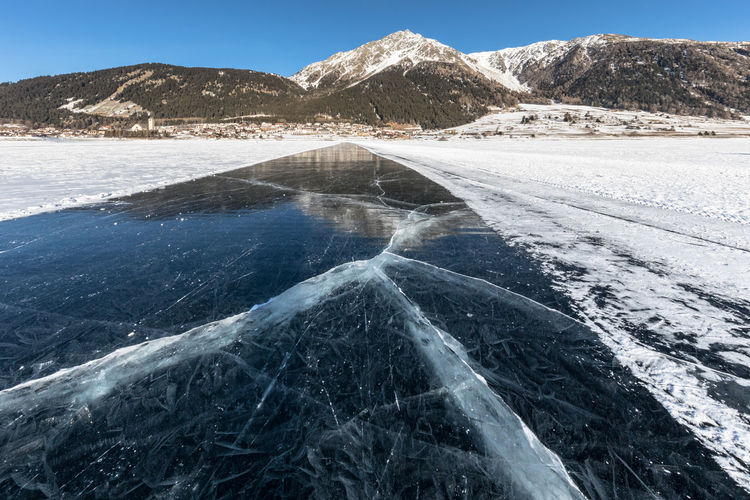  view of frozen lake and mountains against sky