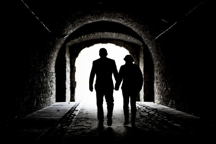 Silhouette people walking in tunnel