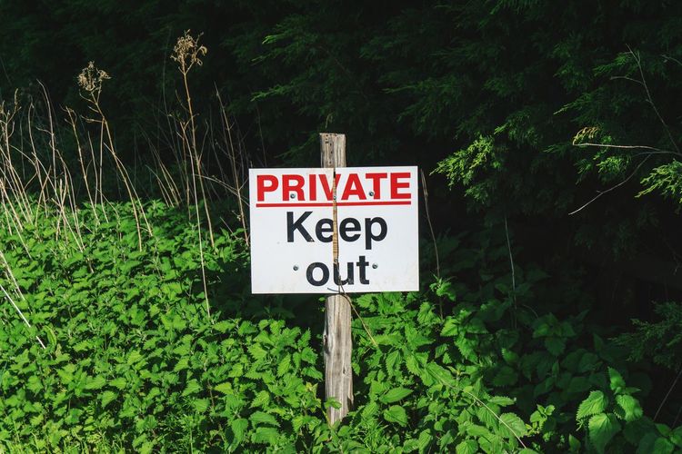 Private keep out information sign by trees in forest