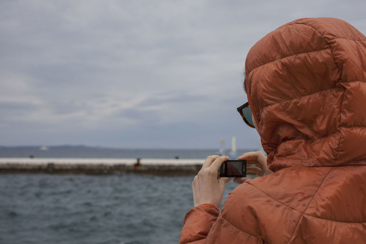 Portrait of a person photographing sea against sky