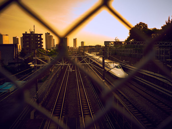 High angle view of train seen through chainlink fence during sunset