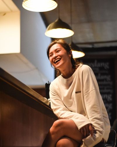 Young woman smiling while sitting in illuminated cafe