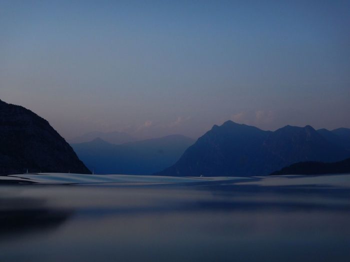 Scenic view of sea and mountains against clear sky