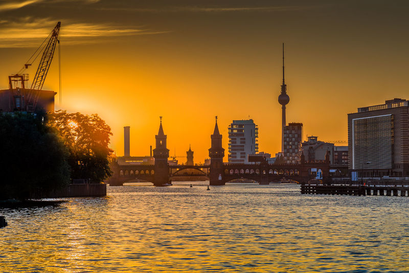 River and buildings against sky during sunset