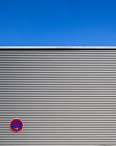 Road sign by building against sky