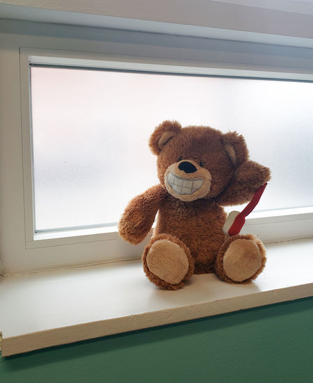 Close-up of stuffed toy on window sill at home