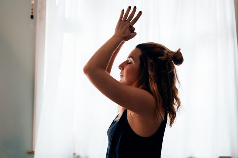 Woman in a yoga position with clasped hands and raised arms performing the sun salutation flow 