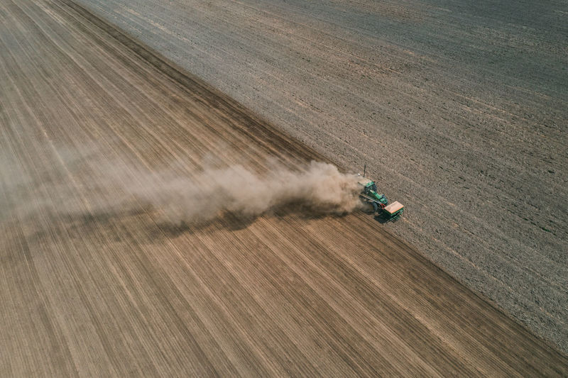 Aerial view the tractor is working in the field creating dust clouds. spring work in the field. 