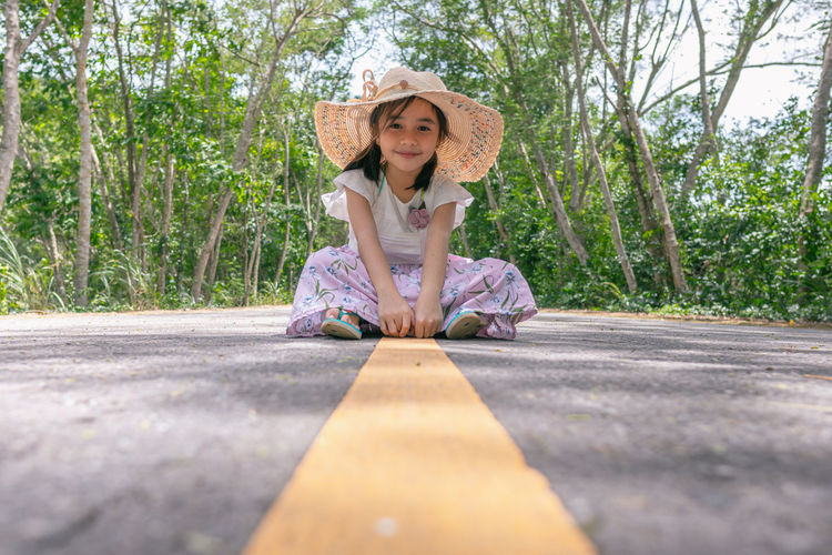 Portrait of smiling girl sitting on road