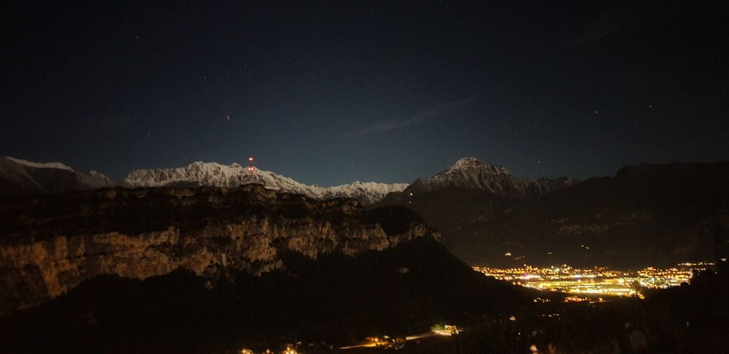 Panoramic view of illuminated mountains against sky at night
