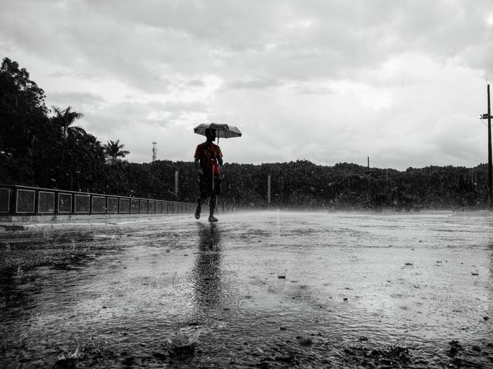 Man standing on wet golf course against sky