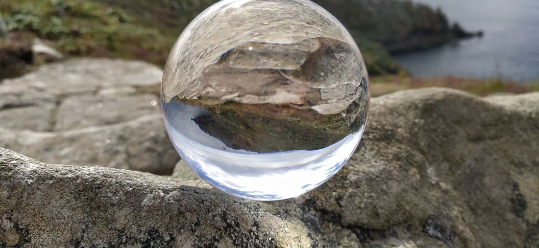 High angle view of crystal ball on rock by lake