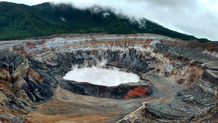 Volcano erupting from rock formation by mountains